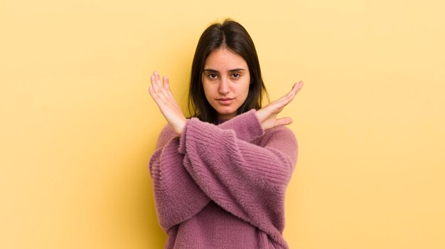 Young hispanic woman looking annoyed and sick of your attitude saying enough hands crossed up front telling you to stop