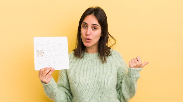 Young hispanic woman looking astonished in disbelief puzzle concept