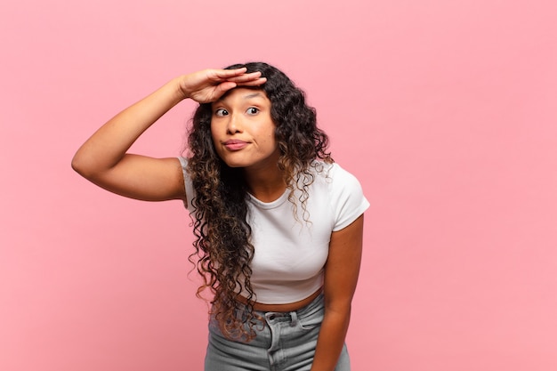 Young hispanic woman looking bewildered and astonished