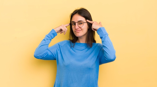 Young hispanic woman looking concentrated and thinking hard on an idea imagining a solution to a challenge or problem