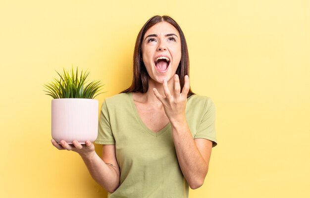 young hispanic woman looking desperate, frustrated and stressed. plant pot concept