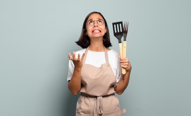 Young hispanic woman looking desperate and frustrated, stressed, unhappy and annoyed, shouting and screaming