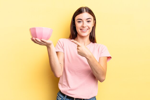 Young hispanic woman looking excited and surprised pointing to the side. empty bowl concept