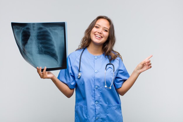 Young hispanic woman looking excited and surprised pointing to the side and upwards to copy space