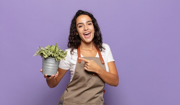 Young hispanic woman looking excited and surprised pointing to the side and upwards to copy space