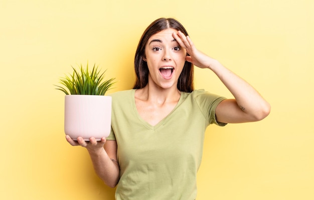 Young hispanic woman looking happy, astonished and surprised. plant pot concept