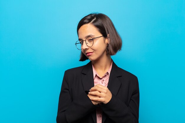 Young hispanic woman looking happy and friendly, smiling and winking an eye at you with a positive attitude