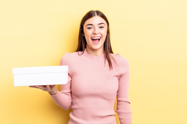 Young hispanic woman looking happy and pleasantly surprised. empty box concept