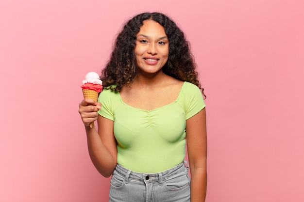 Young hispanic woman looking happy and pleasantly surprised, excited with a fascinated and shocked expression. ice cream concept