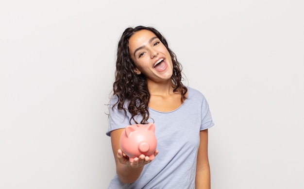 Young hispanic woman looking happy and pleasantly surprised, excited with a fascinated and shocked expression