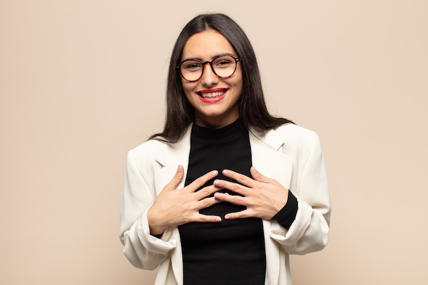 Young hispanic woman looking happy, surprised, proud and excited, pointing to self
