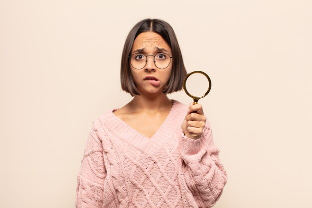 Photo young hispanic woman looking puzzled and confused, biting lip with a nervous gesture, not knowing the answer to the problem