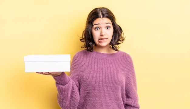 Young hispanic woman looking puzzled and confused. blank box concept