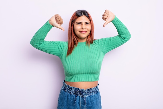 Young hispanic woman looking sad, disappointed or angry, showing thumbs down in disagreement, feeling frustrated