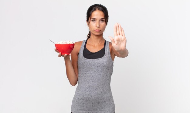 真剣に見える若いヒスパニック系の女性は、開いた手のひらを停止ジェスチャーを示しています。フィットネスダイエットと朝食のコンセプト