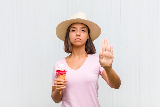 Young hispanic woman looking serious, stern, displeased and angry showing open palm making stop gesture