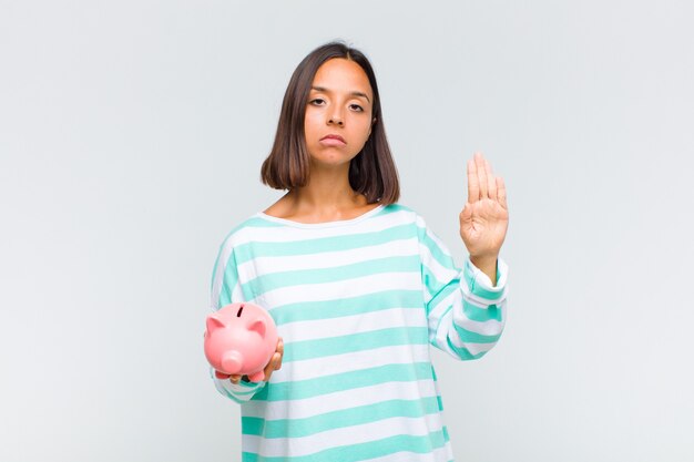 Young hispanic woman looking serious, stern, displeased and angry showing open palm making stop gesture