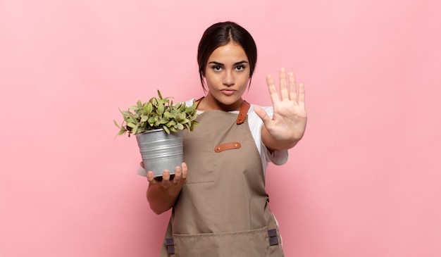 Young hispanic woman looking serious, stern, displeased and angry showing open palm making stop gesture