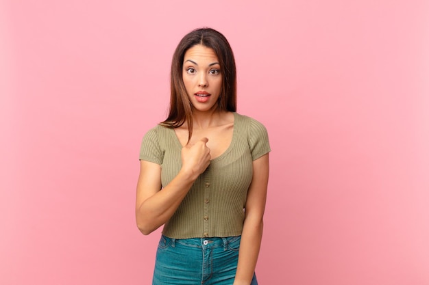 Young hispanic woman looking shocked and surprised with mouth wide open, pointing to self