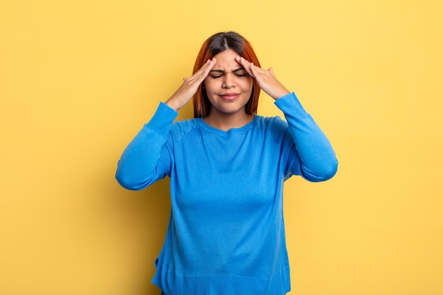 young hispanic woman looking stressed and frustrated, working under pressure with a headache and troubled with problems