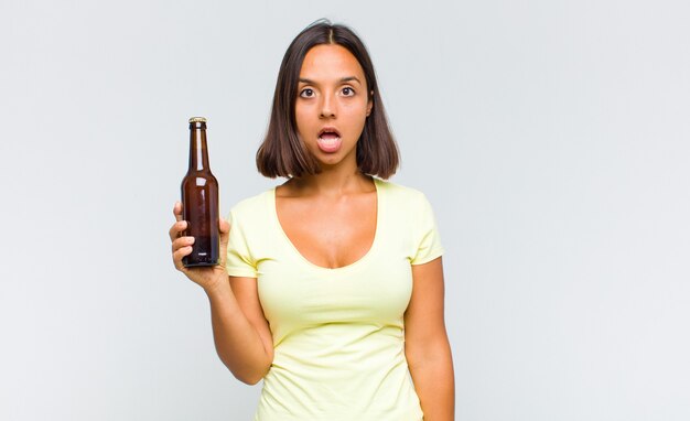 Young hispanic woman looking very shocked or surprised, staring with open mouth saying wow