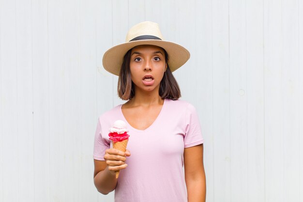 Young hispanic woman looking very shocked or surprised, staring with open mouth saying wow