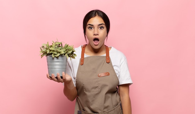 Young hispanic woman looking very shocked or surprised, staring with open mouth saying wow