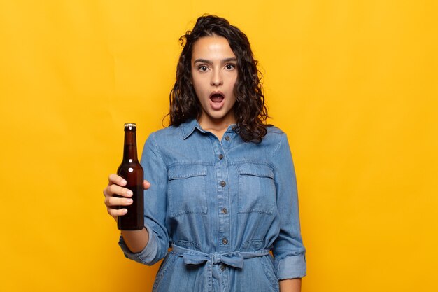 Young hispanic woman looking very shocked or surprised, staring with open mouth saying wow