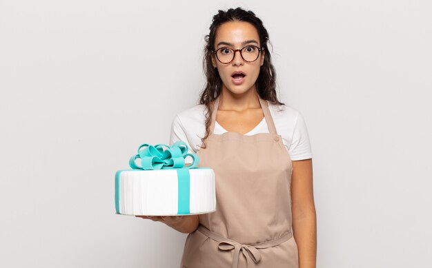 Young hispanic woman looking very shocked or surprised, staring with open mouth saying wow