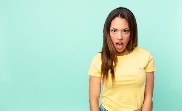 Young hispanic woman looking very shocked or surprised