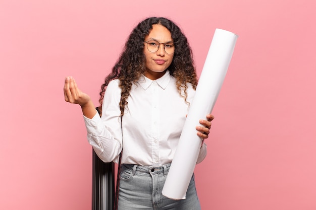 Young hispanic woman making capice or money gesture, telling you to pay your debts!. architect concept