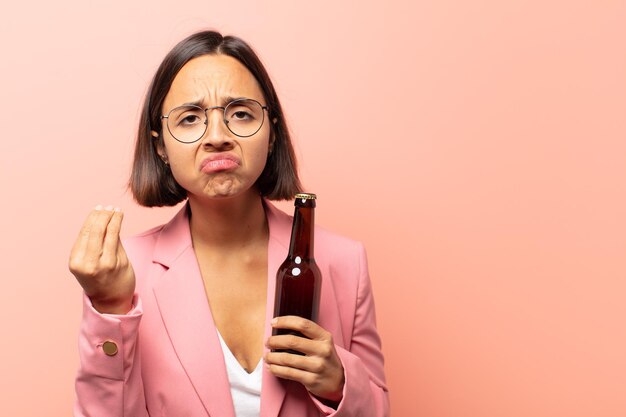 Young hispanic woman making capice or money gesture, telling you to pay your debts!