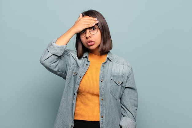 Young hispanic woman panicking over a forgotten deadline, feeling stressed, having to cover up a mess or mistake