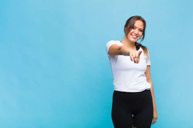 Young hispanic woman pointing at camera with a satisfied, confident, friendly smile, choosing you