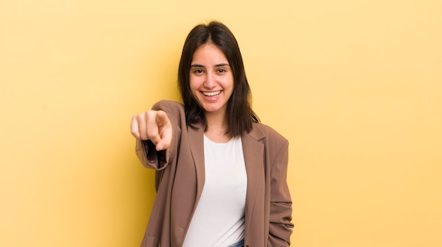 Young hispanic woman pointing at camera with a satisfied confident friendly smile choosing you