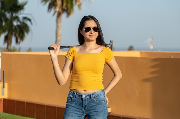 Photo young hispanic woman posing with a golf club playing miniature golf