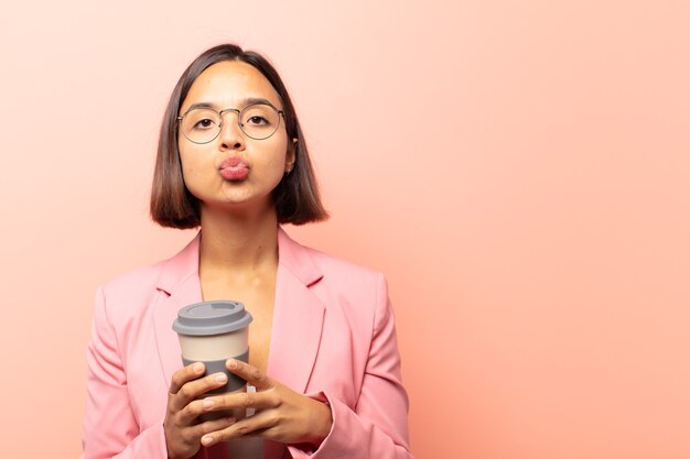 young hispanic woman pressing lips together with a cute, fun, happy, lovely expression, sending a kiss