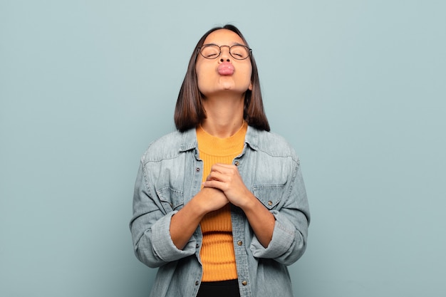 Young hispanic woman pressing lips together with a cute, fun, happy, lovely expression, sending a kiss