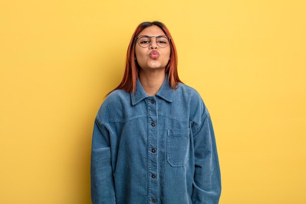 Young hispanic woman pressing lips together with a cute, fun, happy, lovely expression, sending a kiss