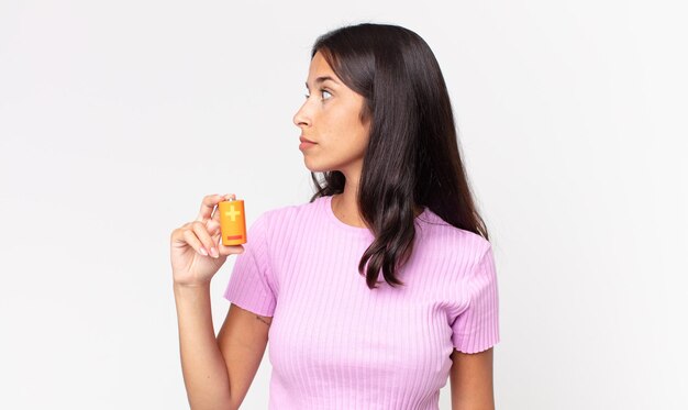 Young hispanic woman on profile view thinking, imagining or daydreaming and holding batteries