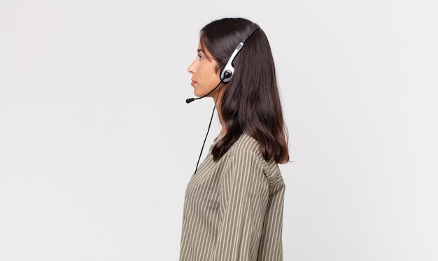 Young hispanic woman on profile view thinking, imagining or daydreaming with a headset. telemarketing concept