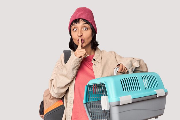 Young Hispanic woman ready for travel with pet carrier screaming very angry and aggressive