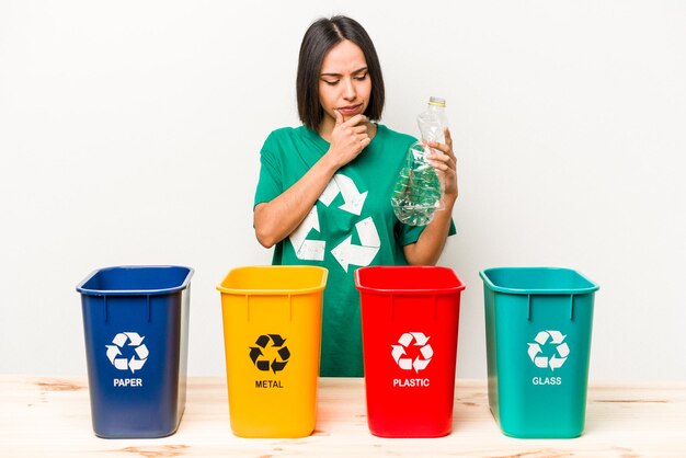 Young hispanic woman recycling plastic isolated on white background