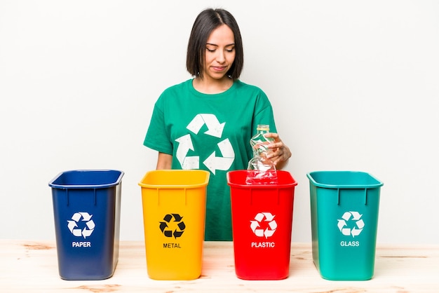 Young hispanic woman recycling plastic isolated on white background