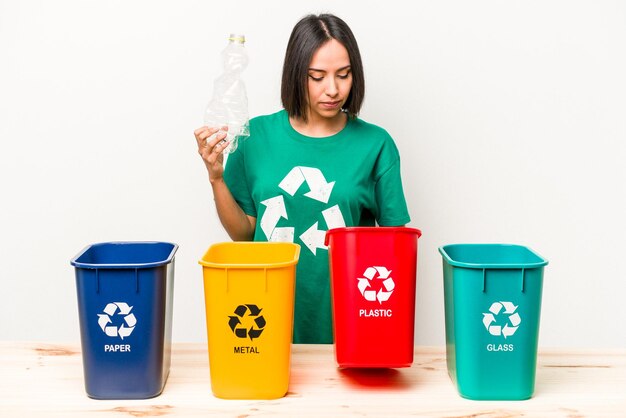 Young hispanic woman recycling plastic isolated on white background