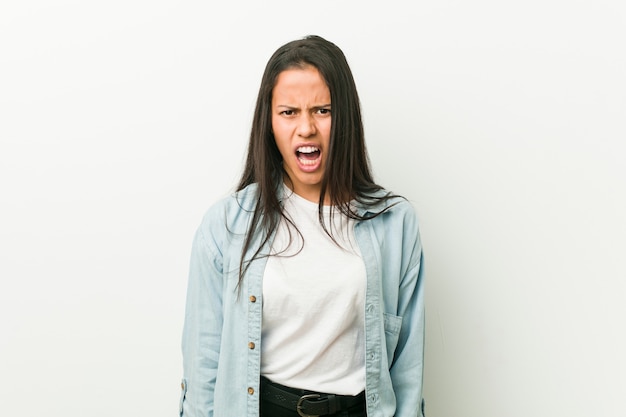 Young hispanic woman screaming very angry and aggressive.