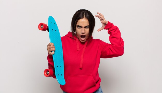 Photo young hispanic woman screaming with hands up in the air, feeling furious, frustrated, stressed and upset