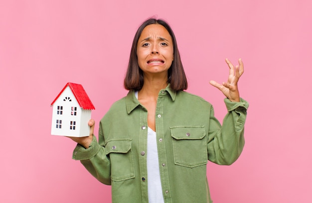 Young hispanic woman screaming with hands up in the air, feeling furious, frustrated, stressed and upset