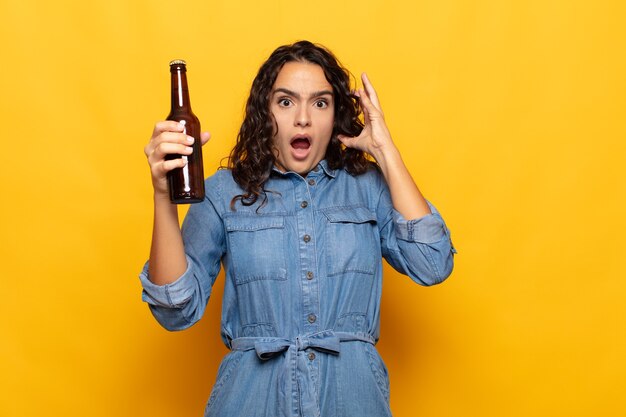 Young hispanic woman screaming with hands up in the air, feeling furious, frustrated, stressed and upset