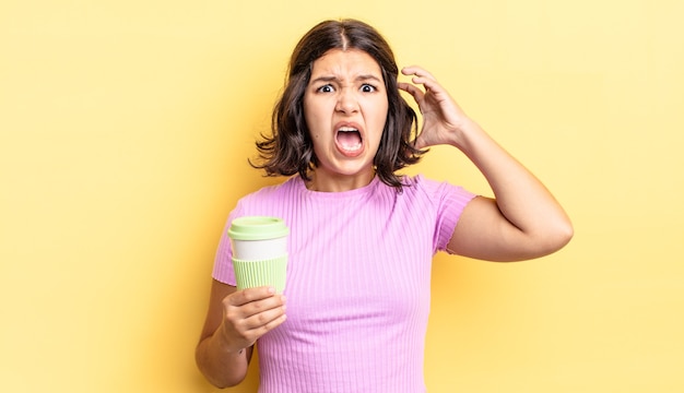 young hispanic woman screaming with hands up in the air. take away coffee concept